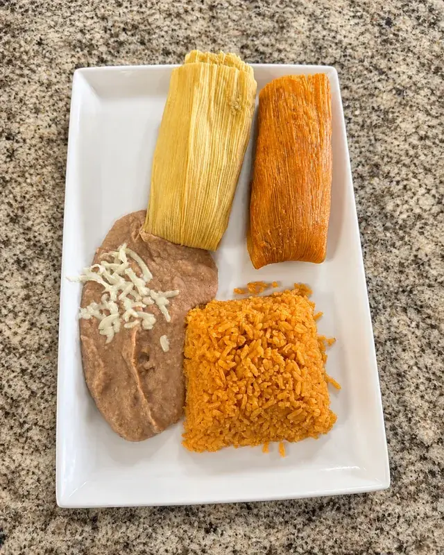 Two wrapped tamales served with rice and beans at Nina's Tacos